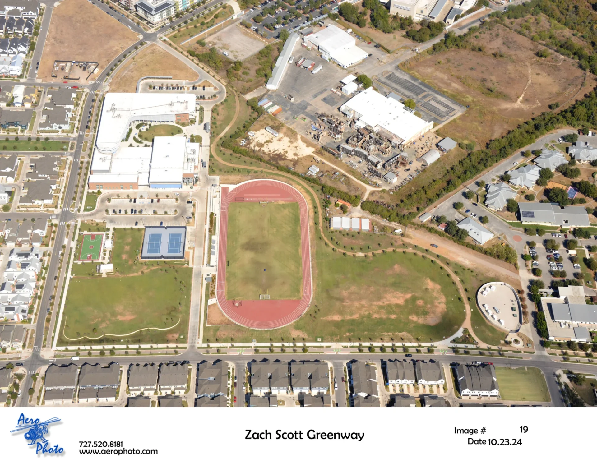 Aerial view of a school track and field with surrounding buildings.